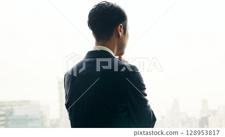一位男商人從辦公室窗戶望向這座城市，憂心忡忡 128953817