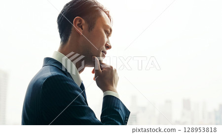 一位男商人從辦公室窗戶望向這座城市，憂心忡忡 128953818