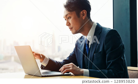 Male business person using laptop computer in urban office building Male business person using laptop computer in urban office building 128953820