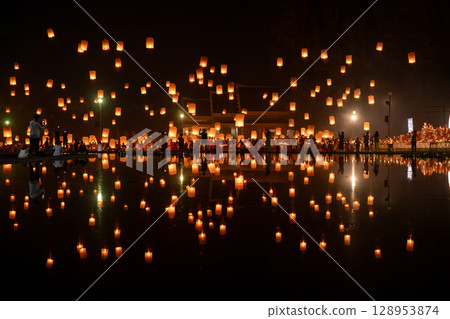 Fire Lanterns Floating up into the sky is reflection in the water at night at Loi Krathong Festival Travel Destinations Of Chiang Mai, Thailand. 128953874