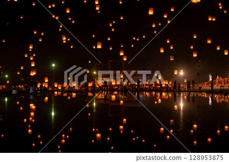 Fire Lanterns Floating up into the sky is reflection in the water at night at Loi Krathong Festival Travel Destinations Of Chiang Mai, Thailand. 128953875