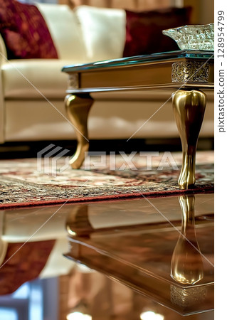 A gold and white coffee table sits in front of a white couch A gold and white coffee table sits in front of a white couch 128954799