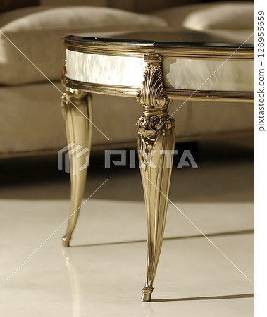 A table with a glass top and legs made of gold 128955659