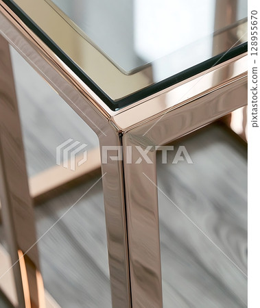 A gold colored table with a glass top 128955670