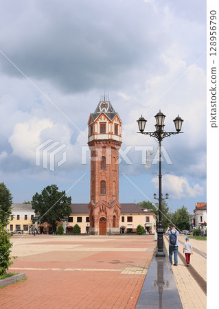 The Historic Clock Tower stands majestically in the Urban Plaza beneath a Scenic Sky The Historic Clock Tower stands majestically in the Urban Plaza beneath a Scenic Sky 128956790