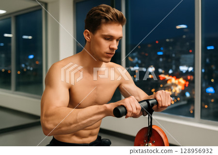 AI generated image of a muscular man working out in a clean, modern gym. The background features a vibrant city skyline at night. The gym is well-lit with a minimalist design AI generated image of a muscular man working out in a clean, modern gym. The background features a vibrant city skyline at night. The gym is well-lit with a minimalist design 128956932