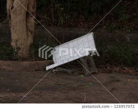 A weathered bench on a neglected sidewalk, highlighting themes of abandonment and decay 128957072