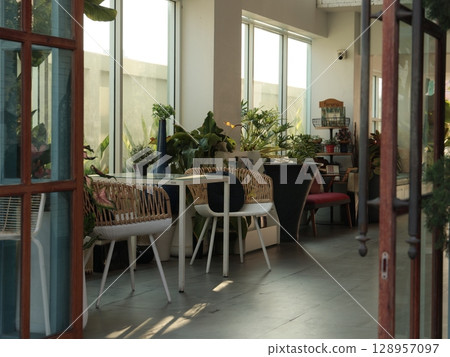 A cozy indoor cafe with abundant greenery and natural light, perfect for relaxation and socializing A cozy indoor cafe with abundant greenery and natural light, perfect for relaxation and socializing 128957097