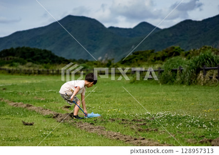 <素材> 一個男孩在草地公園捕捉昆蟲 <素材> 一個男孩在草地公園捕捉昆蟲 128957313