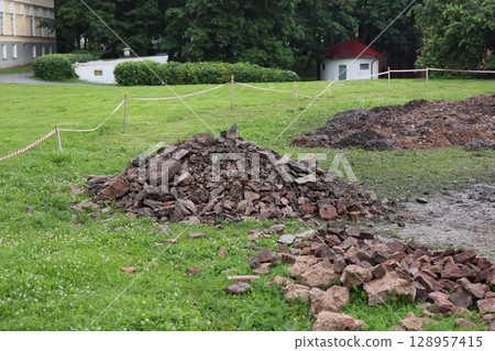 Excavation Site with Numerous Piles of Broken and Crumbling Bricks and Debris Nearby 128957415