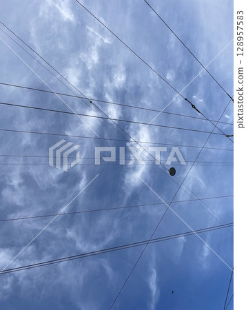 Dramatic Clouds Interwoven with Cables Form an Artistic Contrast Against a Clear Blue Sky Dramatic Clouds Interwoven with Cables Form an Artistic Contrast Against a Clear Blue Sky 128957583