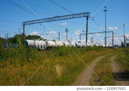 A Freight Train Carrying Cargo Tanks Rides Along the Rails Under a Clear Blue Sky Above A Freight Train Carrying Cargo Tanks Rides Along the Rails Under a Clear Blue Sky Above 128957681