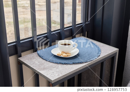A cozy coffee setting on a modern balcony table, perfect for a delightful breakfast or brunch 128957753