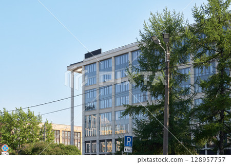 A contemporary modern office building stands tall against a beautifully clear blue sky A contemporary modern office building stands tall against a beautifully clear blue sky 128957757