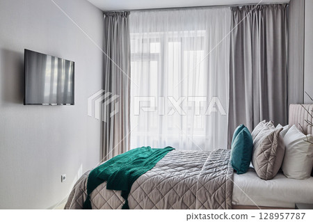 A Cozy Modern Bedroom Featuring Beautiful Soft Neutral Tones and a TV for Entertainment 128957787