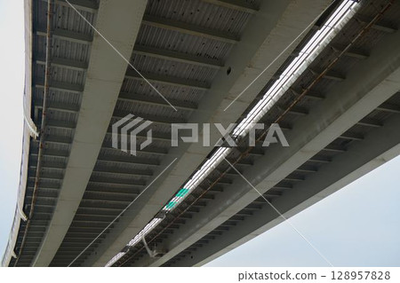 Located directly beneath a modern concrete overpass spans across the bustling city scape Located directly beneath a modern concrete overpass spans across the bustling city scape 128957828