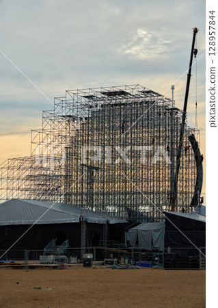 An expansive scaffolding structure is under construction at sunset, creating a stunning scene An expansive scaffolding structure is under construction at sunset, creating a stunning scene 128957844