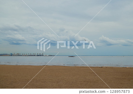 A Serene Beachfront Landscape Featuring Calm Waters and Soft Clouds in the Sky Above 128957873