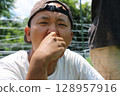 A young man biting into a raw pepper in Yachimata, Chiba Prefecture 128957916