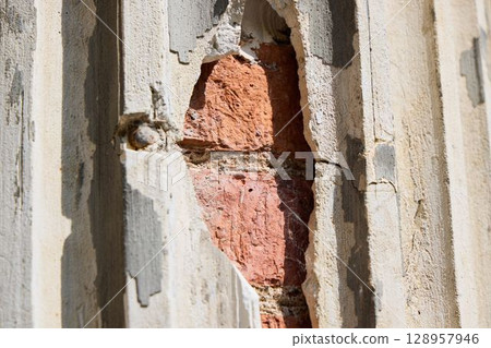 A CloseUp View of a Damaged Wall That Reveals the Red Brick Material Underneath the Surface A CloseUp View of a Damaged Wall That Reveals the Red Brick Material Underneath the Surface 128957946