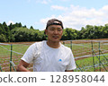 A young male farmer talks under the blue sky in Yachimata, Chiba Prefecture 128958044