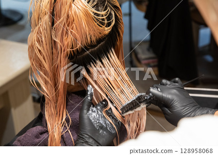 A woman having her hair colored at a beauty salon 128958068