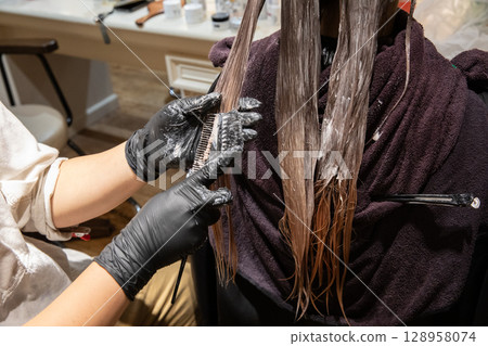 A woman having her hair colored at a beauty salon 128958074
