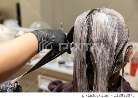 A woman having her hair colored at a beauty salon A woman having her hair colored at a beauty salon 128958075