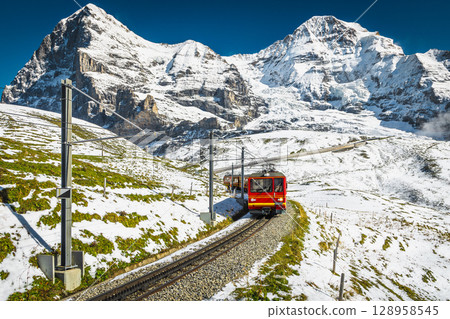 Electric passenger cogwheel train on the snowy slope in Switzerland 128958545