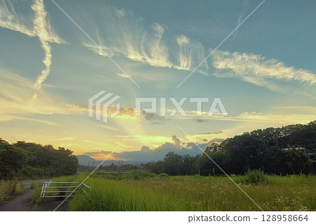A melancholic scene with a string of clouds shining in the setting sun A melancholic scene with a string of clouds shining in the setting sun 128958664