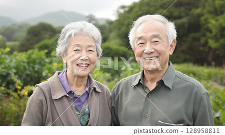 一對老年夫婦並肩站著，以鄉村風景為背景微笑 128958811