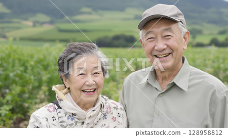 一對老年夫婦並肩站著，以鄉村風景為背景微笑 128958812