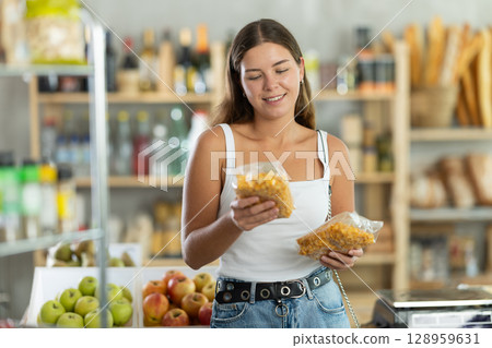 Young woman choosing corn flakes in grocery store Young woman choosing corn flakes in grocery store 128959631