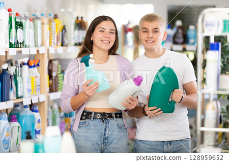Couple man and woman choosing detergent and spray in store Couple man and woman choosing detergent and spray in store 128959652