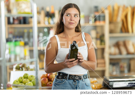 Young woman choosing olive oil in grocery store 128959673