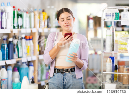 Young woman scanning QR-code on shampoo in department store Young woman scanning QR-code on shampoo in department store 128959780