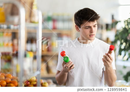 Young man examining spice jars in grocery store Young man examining spice jars in grocery store 128959841