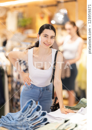 Girl customer chooses denim knee breeches or shorts in store Girl customer chooses denim knee breeches or shorts in store 128959871