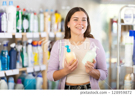 Female buyer chooses liquid hand soap in household goods department of supermarket Female buyer chooses liquid hand soap in household goods department of supermarket 128959872