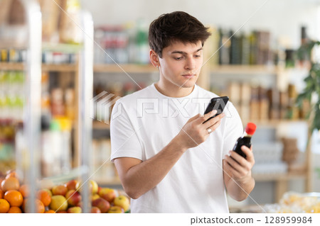 Male buyer checks suitability - scans QR code on jar of soy sauce label in grocery store Male buyer checks suitability - scans QR code on jar of soy sauce label in grocery store 128959984