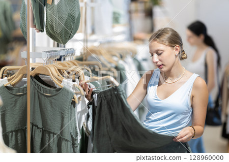 Girl customer chooses green trousers in branded store 128960000