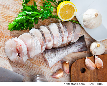 Pieces of fresh hake with seasonings prepared for cooking 128960066