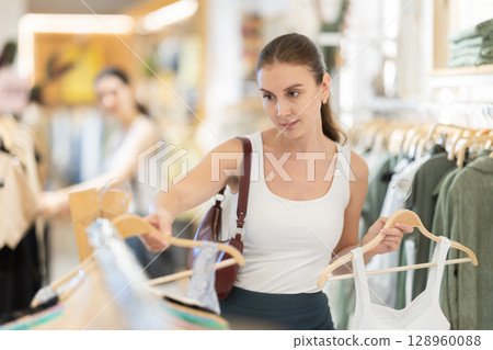 Young woman choosing top in clothing store Young woman choosing top in clothing store 128960088