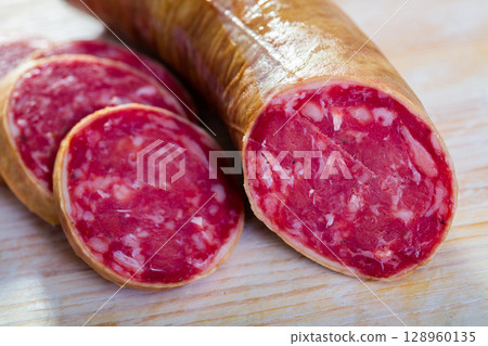 Salchichon spanish sausage slices on wooden desk Salchichon spanish sausage slices on wooden desk 128960135