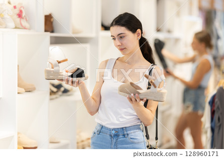 Girl customer choose shoes in branded store Girl customer choose shoes in branded store 128960171