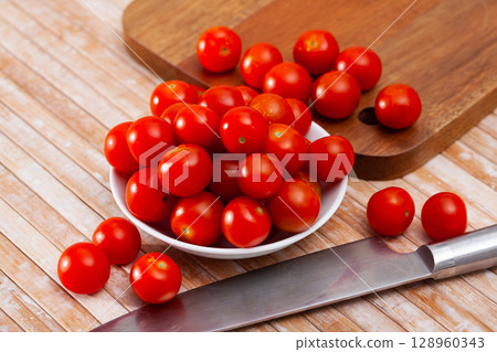 Whole fresh red cherry tomatoes on wooden table. Vegetarian ingredient Whole fresh red cherry tomatoes on wooden table. Vegetarian ingredient 128960343