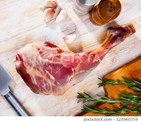 Raw leg of milk-fed lamb with condiments Raw leg of milk-fed lamb with condiments 128960359