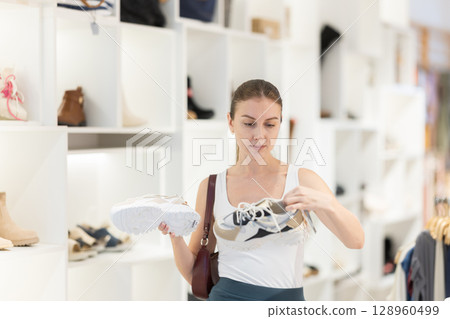 Young woman choosing sneakers in the store 128960499