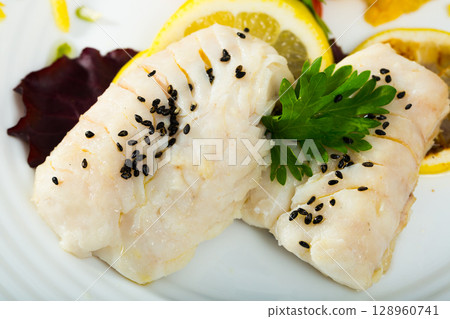 Closeup of codfish steamed and served with herbs and lemon 128960741