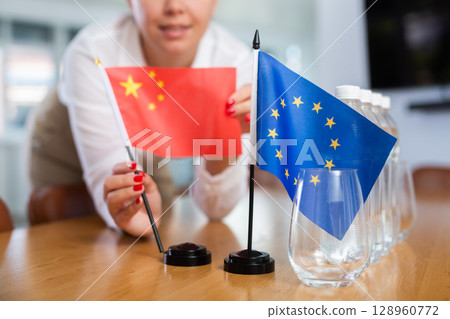Female secretary places flags of the European Union and China flag on the table before negotiations of top political figures Female secretary places flags of the European Union and China flag on the table before negotiations of top political figures 128960772